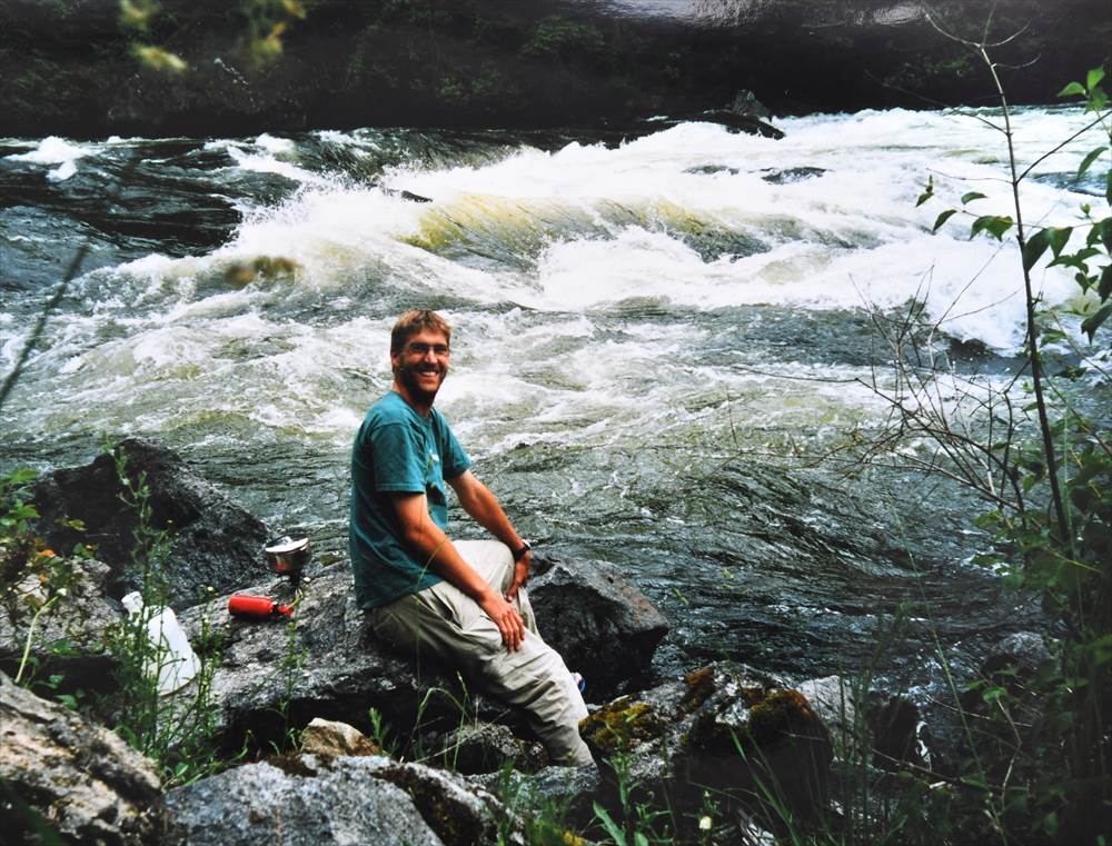 Picture of Andy sitting on the rock by the river