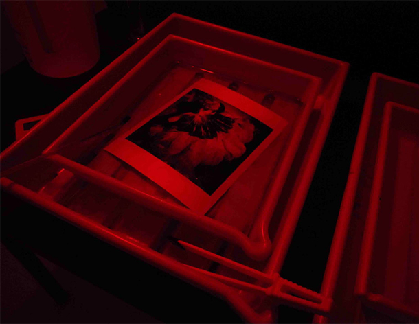 Picture of developing a print in the darkroom under a red safe-light