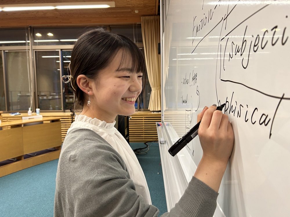 教室でホワイトボードに字を書く伊藤 花さんの写真