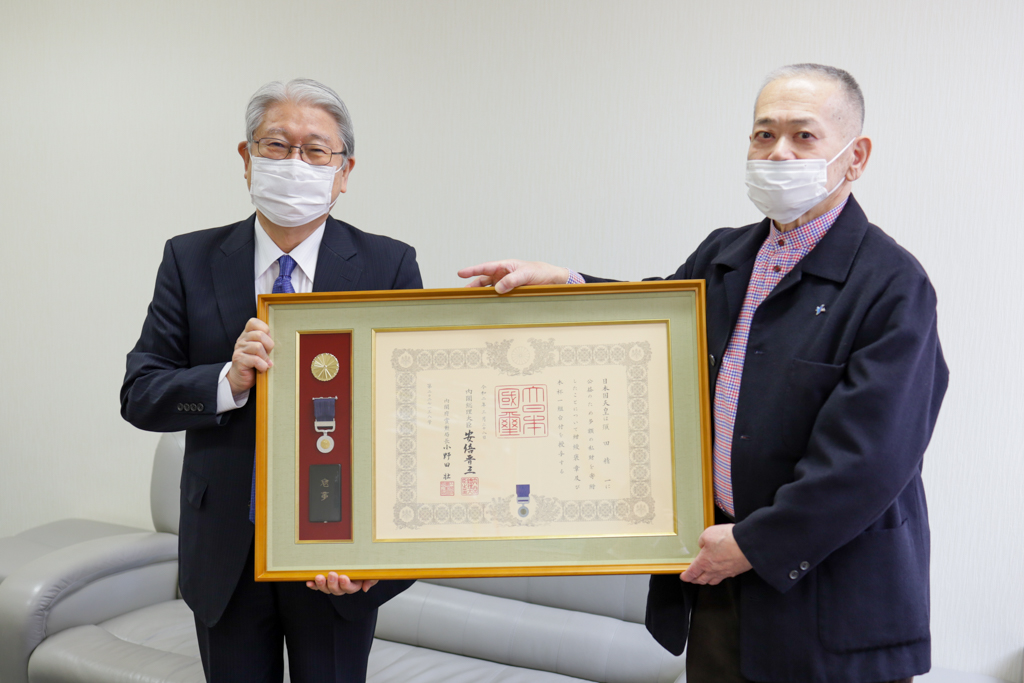 須田会長と鈴木学長が並んで紺綬褒章を見せている写真