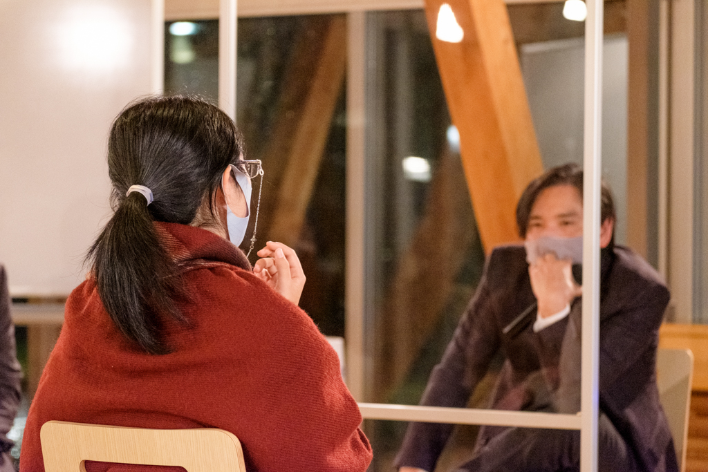 透明なパーテション越しに対話する学生と中川准教授の写真