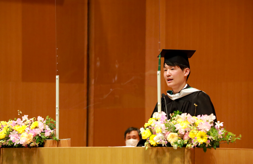 修了生代表の萩原 亘祐さんが壇上でスピーチしている写真