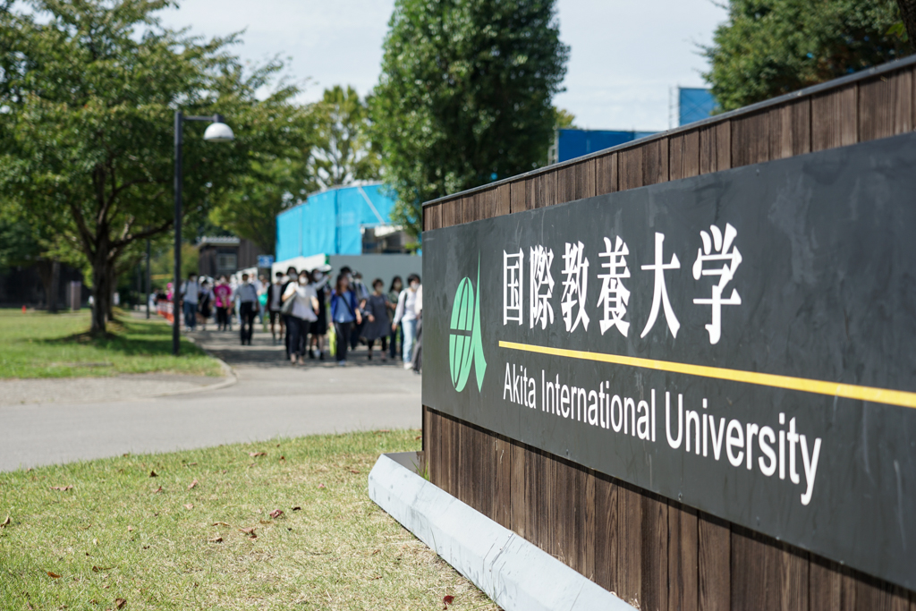 国際教養大学の看板前の写真。大勢の参加者がキャンパスを歩いている