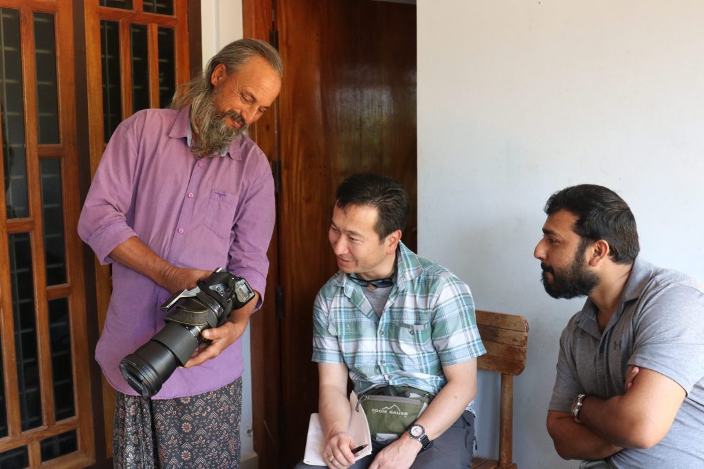 Picture of a photographer showing his camera to Dr. Natori and Dr. Varghese