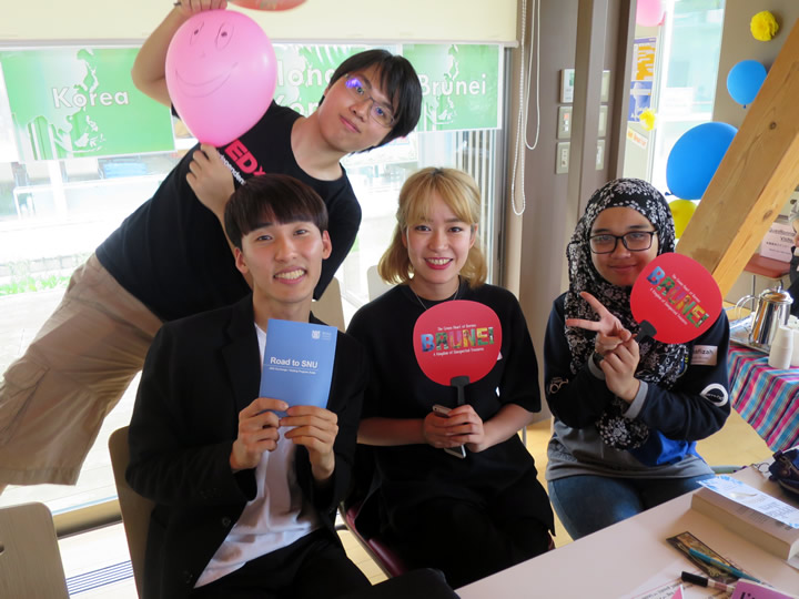 Volunteer exchange students and returnees from partner universities in Asia show off their promotional materials and decorations.