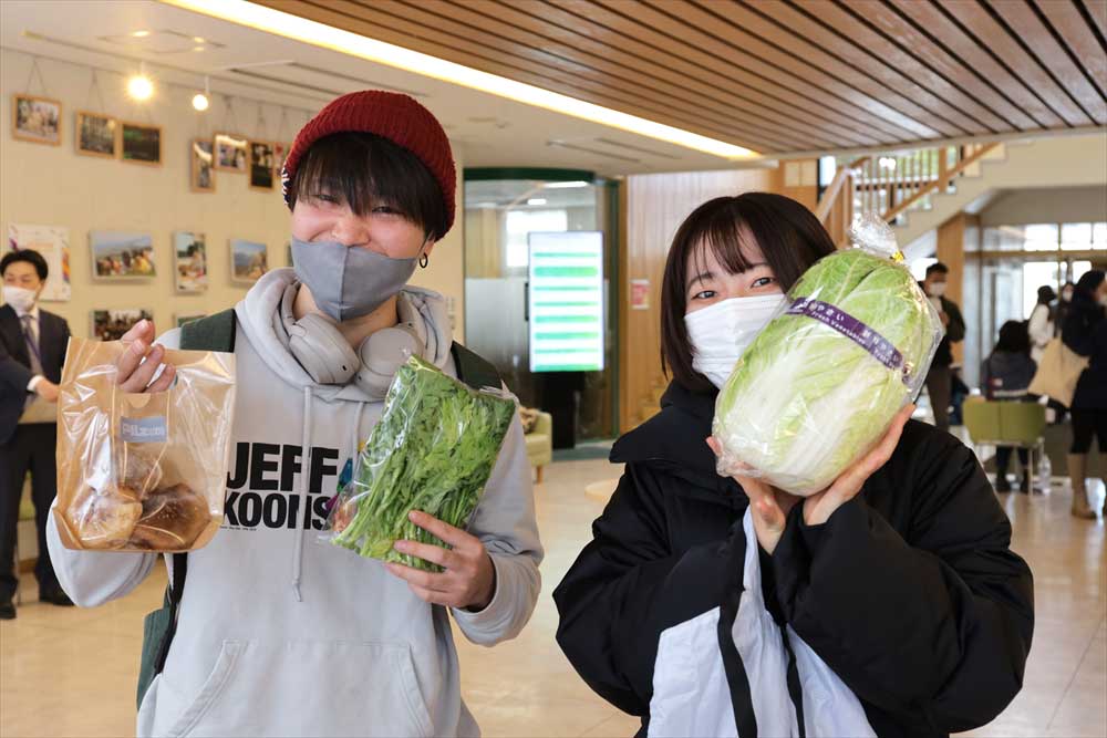 配布された野菜を持った学生の写真